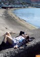 A woman laying on the ground next to a body of water.